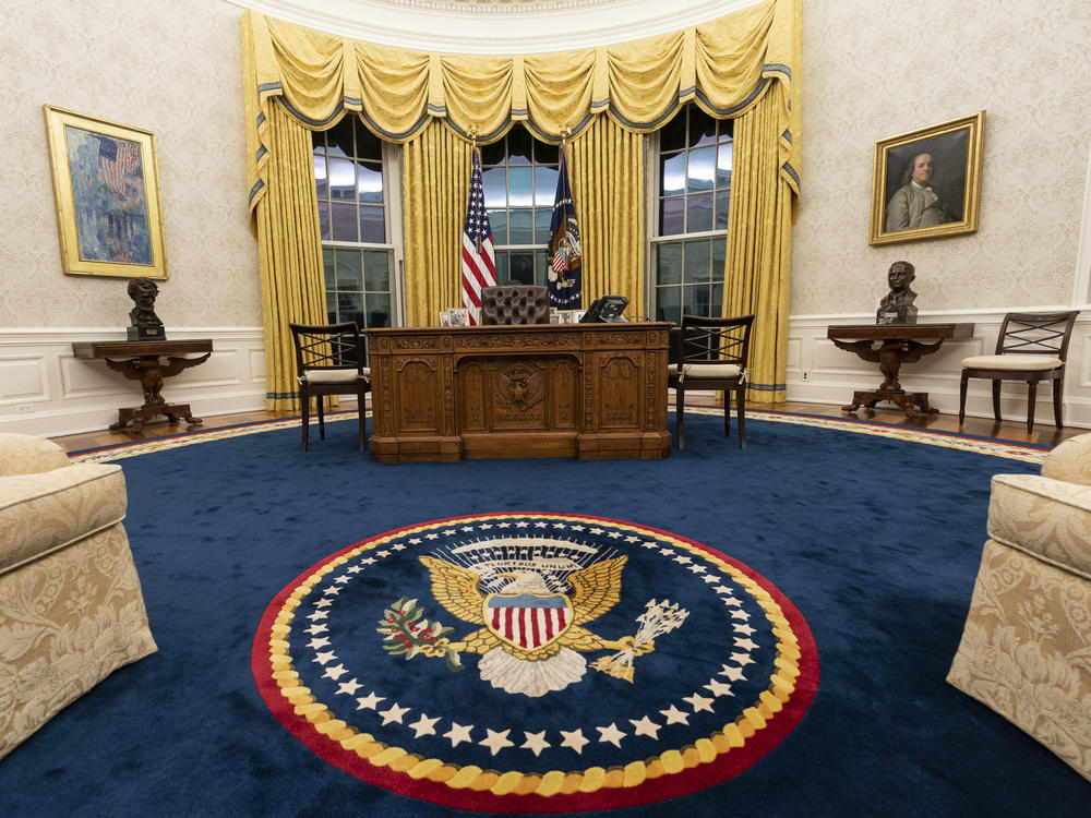 Biden kept the drapes and most of the furniture, but the rug and artwork in the Oval Office have changed. Flanking the Resolute desk are busts of Abraham Lincoln (left) and Harry Truman. Above Lincoln is <em>The Avenue in the Rain</em> by Childe Hassam. Above Truman is a portrait of Benjamin Franklin.