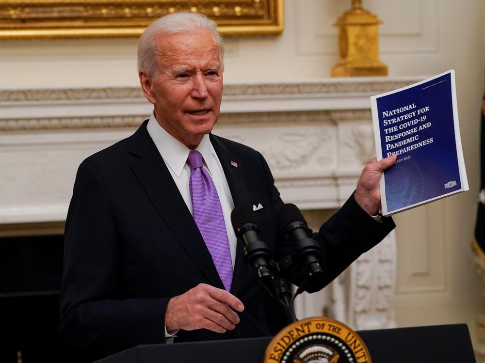 President Joe Biden holds a booklet as he speaks about the coronavirus in the State Dining Room of the White House, Thursday.