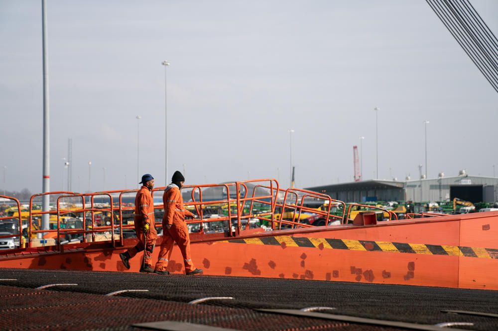 Workers at the Port of Baltimore walk down the stern ramp of a vessel. A group that normally welcomes crew members to the city is now acting as couriers, dropping off care packages to those stuck on board ships.