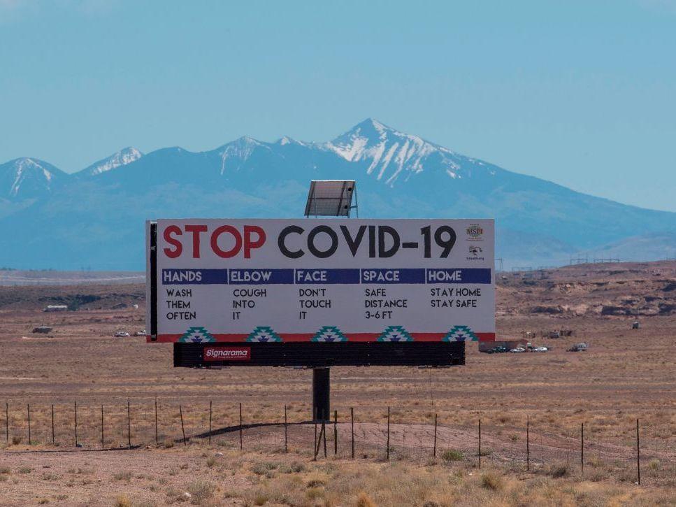 A sign warns against COVID-19 near the Navajo town of Tuba City, Ariz. As the pandemic rages across the U.S., mitigation measures continue to be critical to save lives.