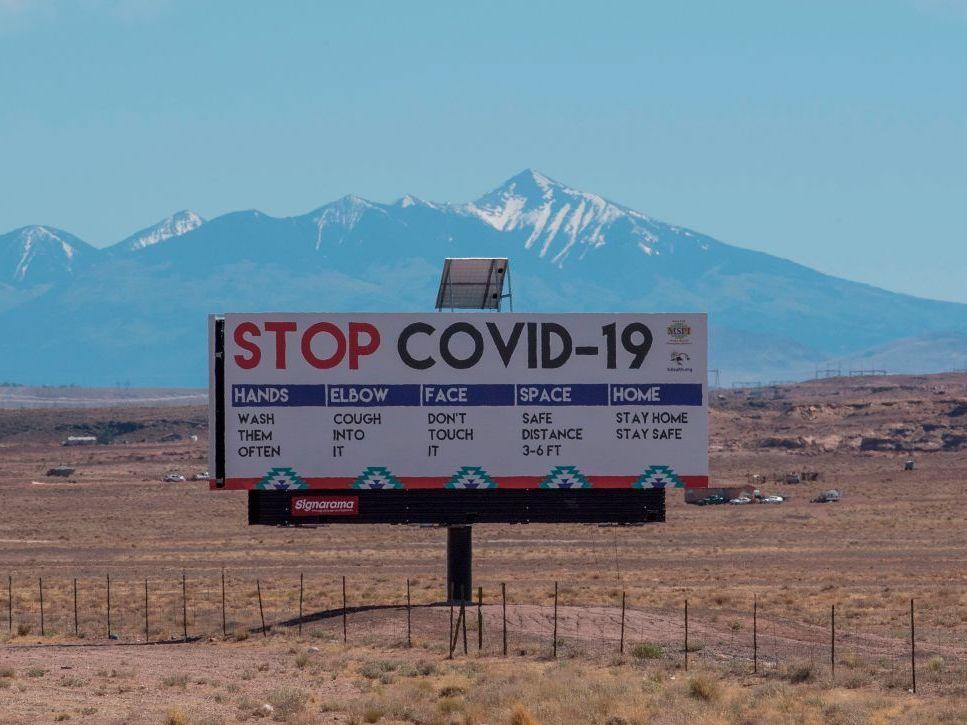 A sign warns against COVID-19 near the Navajo town of Tuba City, Ariz. As the pandemic rages across the U.S., mitigation measures continue to be critical to save lives.