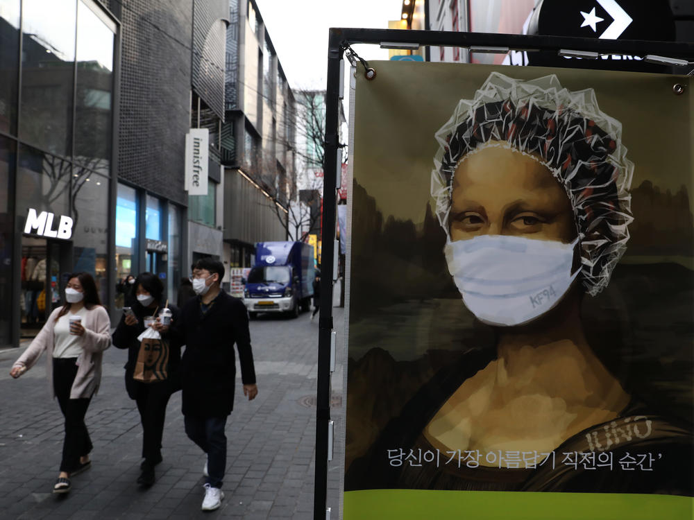 South Korea's KF94 mask does a good job concealing the <em>Mona Lisa</em>'s smile — but how effective is it at preventing coronavirus spread? Here, masked pedestrians stroll through a shopping district in Seoul.