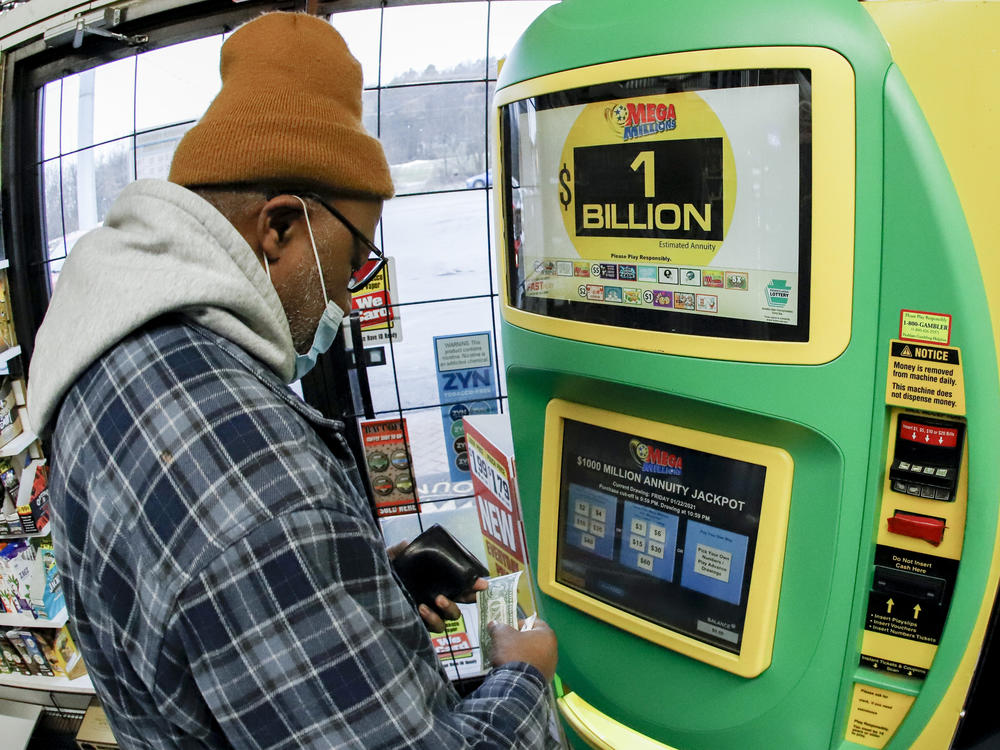 A patron, who did not want to give his name, uses the lottery ticket vending kiosk at a Smoker Friendly store to purchase tickets for the Mega Millions lottery drawing Friday in Cranberry Township, Pa.