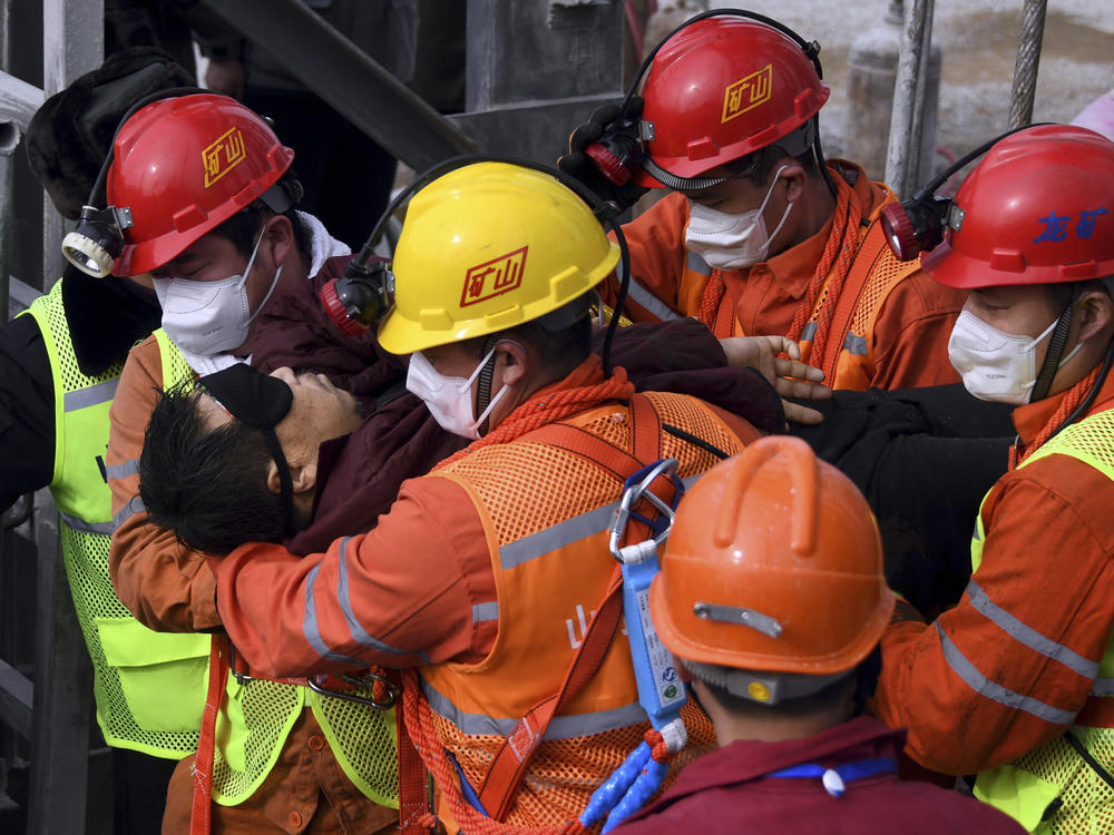 Rescuers carry a worker who was trapped in a gold mine to an ambulance in the city of Qixia in China's Shandong province. Eleven workers trapped for two weeks by an explosion inside the mine were brought safely to the surface on Sunday.