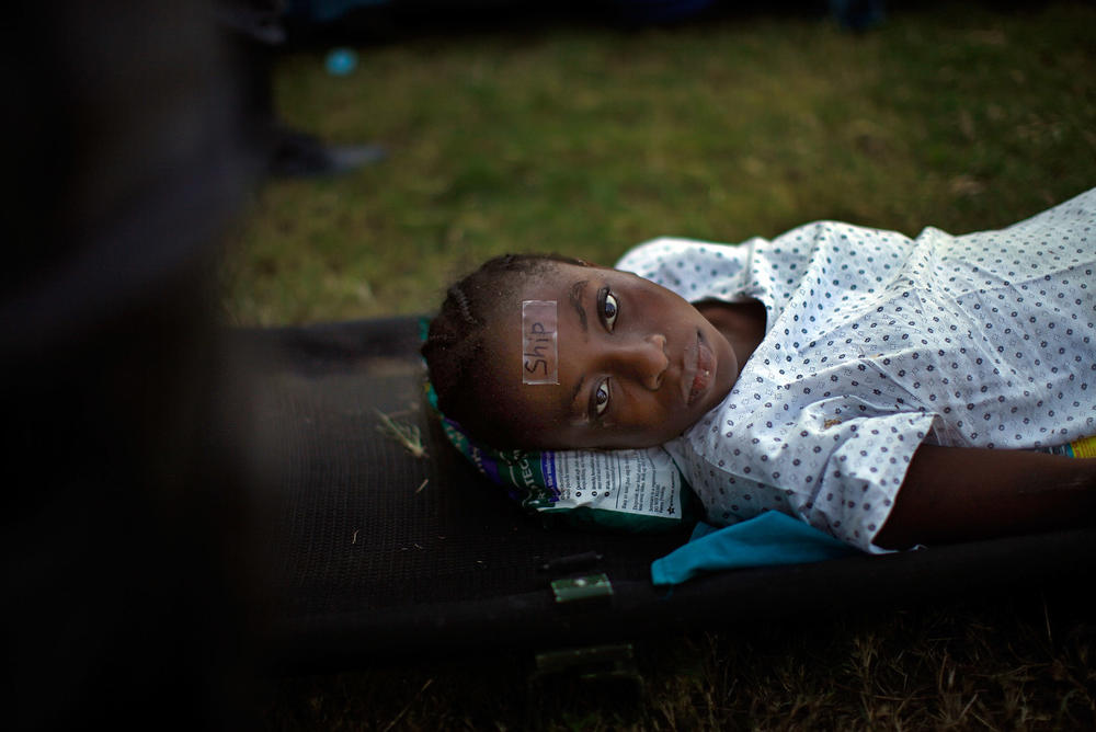 A woman, with a tag that identifies her as a transfer patient to the USNS Comfort, waits for a helicopter evacuation in Port-au-Prince, Haiti, after the country's devastating earthquake in January 2010.