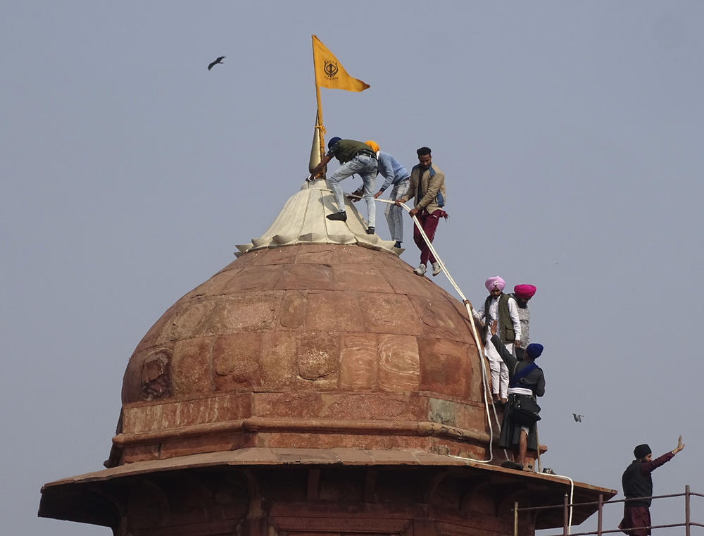 Farmers and their supporters hoist flags over the historic Red Fort monument in New Delhi on Tuesday.