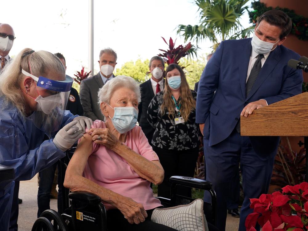 Florida Gov. Ron DeSantis watches as nurse Christine Philips (left) administers the Pfizer-BioNTech vaccine for COVID-19 to Vera Leip, 88, a resident of John Knox Village, Wednesday, Dec. 16, 2020, in Pompano Beach, Fla.