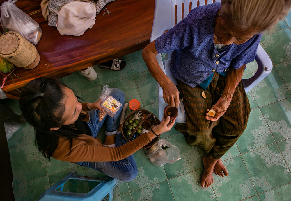 A passes <em>paan — </em>a stimulant chew made of betel leaves and other ingredients — to her grandmother. Since moving back to her home village, A spends most of her time taking care of her.