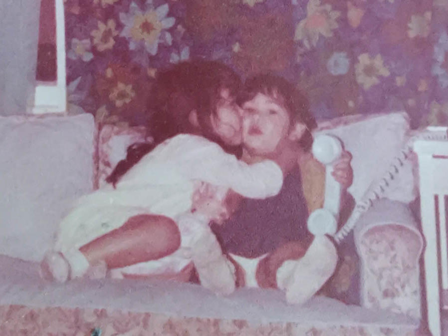 Brenda Ulloa Martinez (left), then 4, and younger sister Corina Ulloa, 2, are pictured in the living room of their one-bedroom apartment where they lived with their parents.