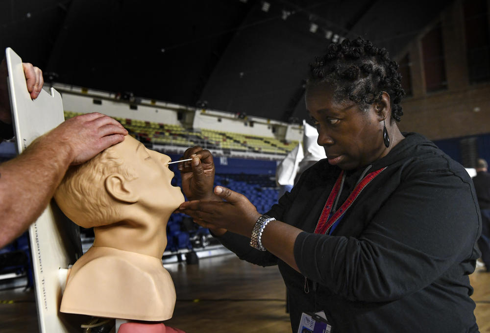 Karyn Hawkins, a nurse at NIH, practices performing a nasal swab for a COVID-19 test during a D.C. Medical Reserve Corps training at the D.C. Armory in March 2020. The MRC also includes doctors, veterinarians, pharmacists, dentists, and still others without medical skills who help with logistics and administrative tasks.