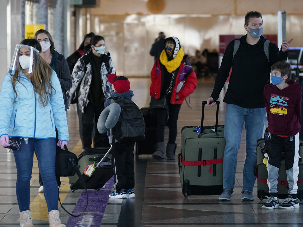 Masked travelers head through the main terminal of Denver International Airport on Dec. 31. Starting Feb. 1, travelers will be required to wear face masks on nearly all forms of public transportation.