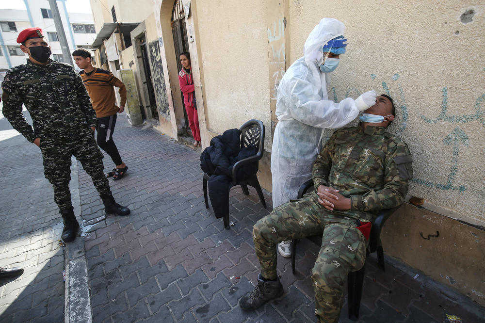 A Palestinian medical worker takes a swab sample from security personnel guarding the homes of quarantined patients infected with the COVID-19 coronavirus in Rafah, in the southern Gaza Strip in January.
