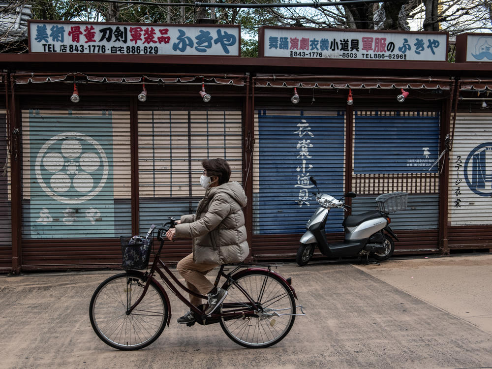 A woman wearing a face mask cycles past closed souvenir shops near Sensoji Temple, normally a popular tourist destination, on Feb. 2 in Tokyo. Prime Minister Yoshihide Suga announced a one-month extension to the state of emergency across much of the country.