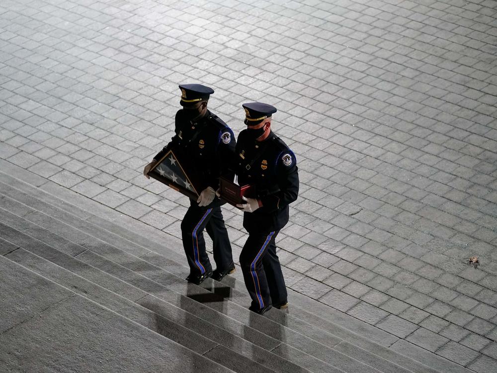 An honor guard carries an urn with the cremated remains of  Capitol Police officer Brian Sicknick and a folded American flag up the steps of the U.S. Capitol on Tuesday.