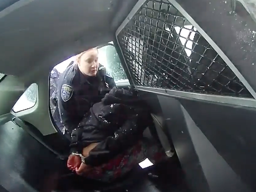 A frame from a Rochester Police Department body-camera video shows a girl in handcuffs in the back of a police cruiser.