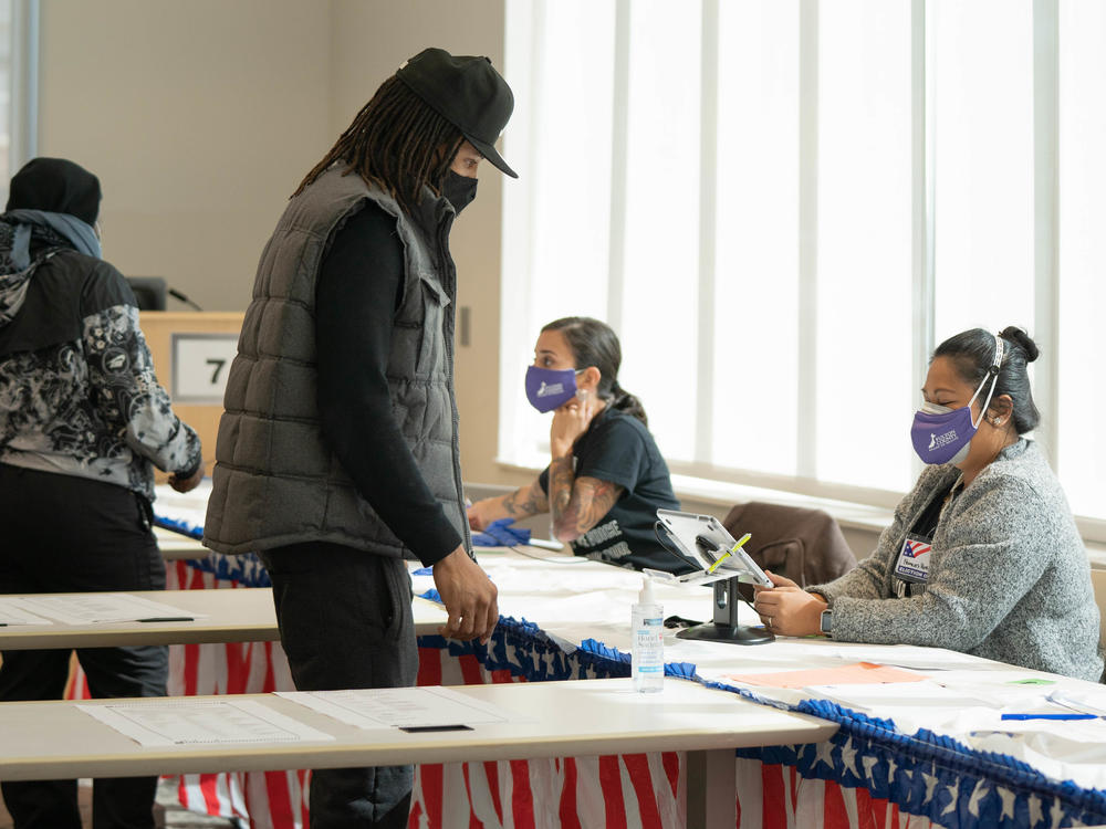 Poll workers help voters get ready to cast their ballots on Nov. 3 in Atlanta. State lawmakers are now considering legislation that could roll back some laws that made it easier for voters to cast ballots by mail.