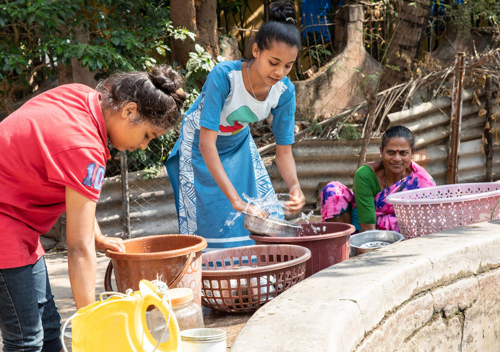 Teenager Shraddha Tandel washes cooking utensils at a communal village well.