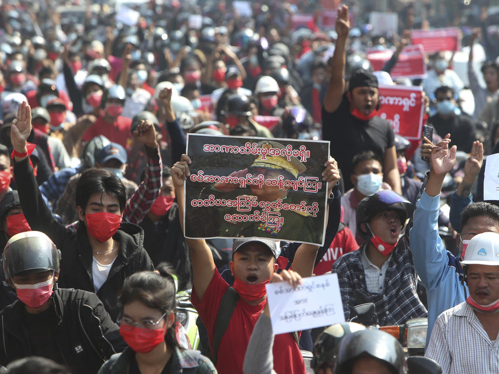 A protester shouts slogans while holding a placard with an image of Myanmar military Commander-in-Chief Senior Gen. Min Aung Hlaing as fellow protesters march around Mandalay on Sunday.