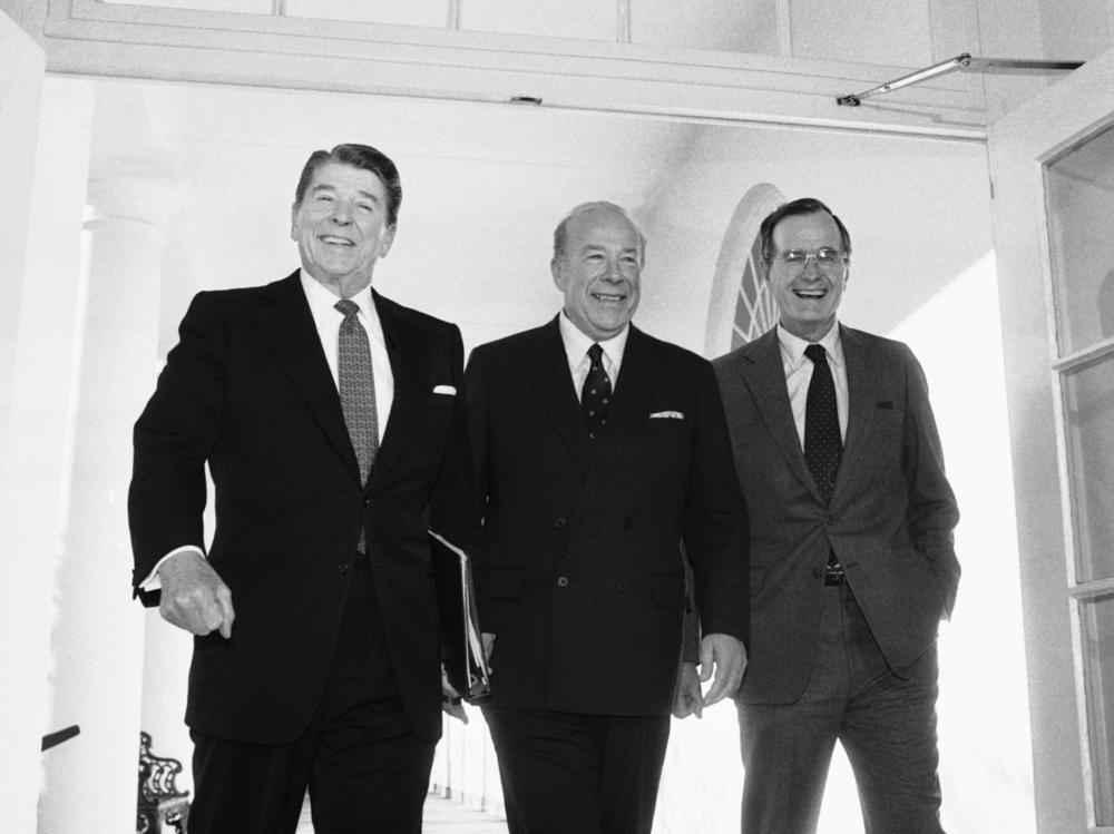 Secretary of State George Shultz, center, walks with President Reagan and Vice President George Bush on his arrival at the White House in January 1985 after two days of arms talks with the Soviet Union in Geneva. Shultz died Saturday at the age of 100.