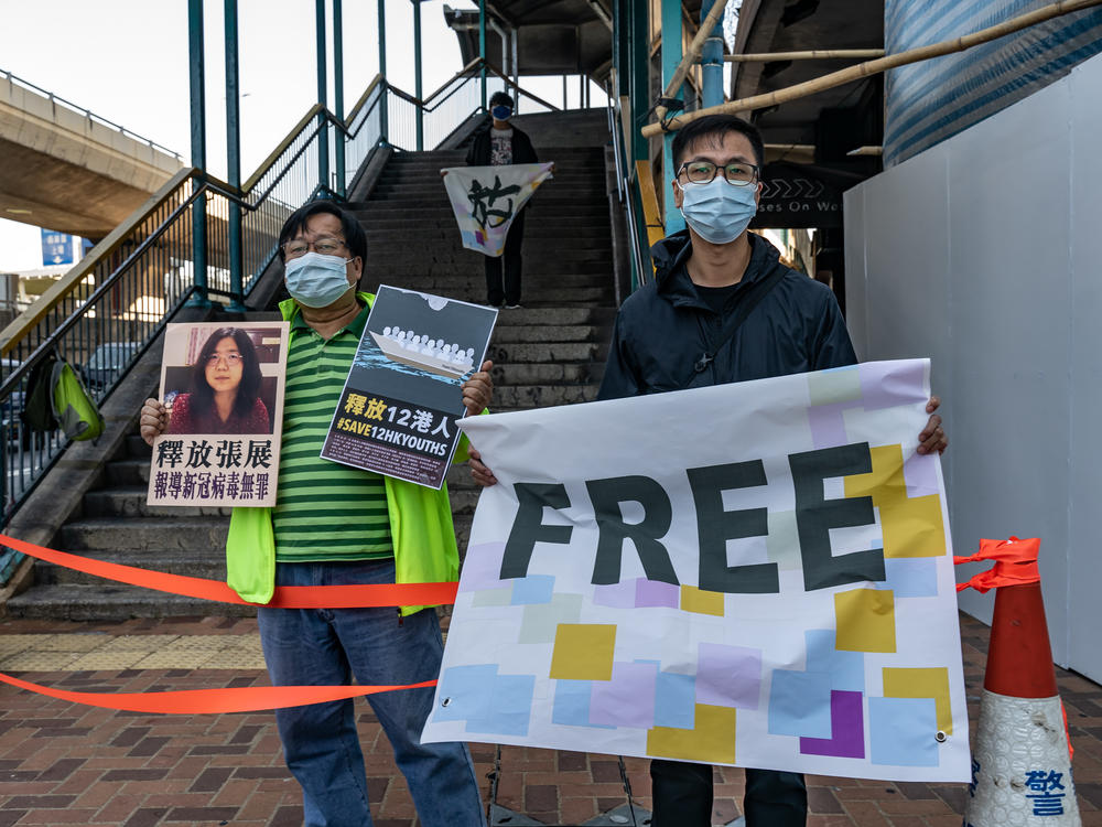Pro-democracy activists hold placards in support of 12 Hong Kong residents detained in mainland China and former lawyer Zhang Zhan outside the Liaison Office of the Central People's Government on Dec. 28 in Hong Kong. They protested as Zhang  and the 12 residents were due in court in Shenzhen, China.
