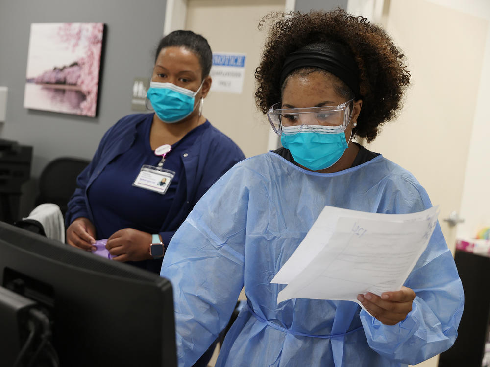 Workers at an urgent care facility in Woodbridge, Va., check health records while testing patients for COVID-19 on April 15, 2020.