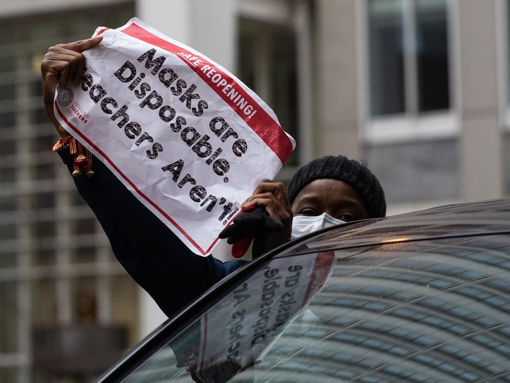 Chicago teachers have voted to accept an agreement for returning to in-person classes in the coming weeks. Here, a woman holds a sign at a car caravan in support of teachers' call for more safety precautions.