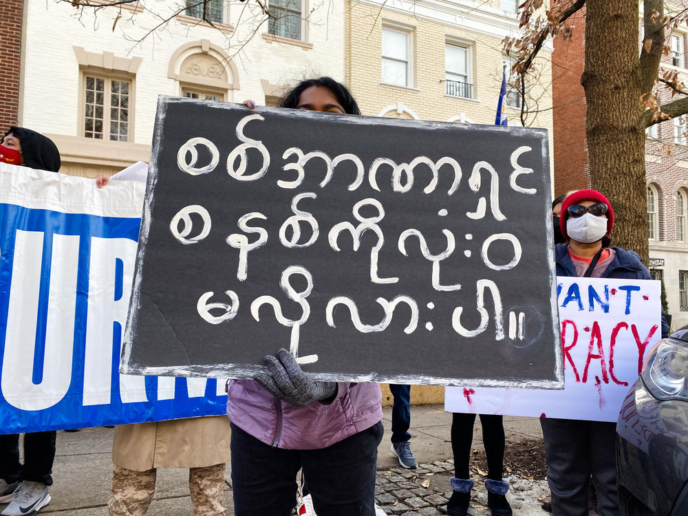A demonstrator holds a sign that reads: 