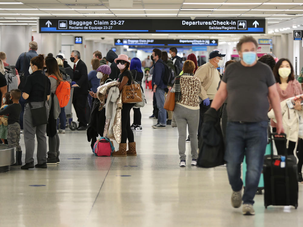 People gather their luggage after arriving at Miami International Airport on a plane from New York earlier this month in Miami, Fla.