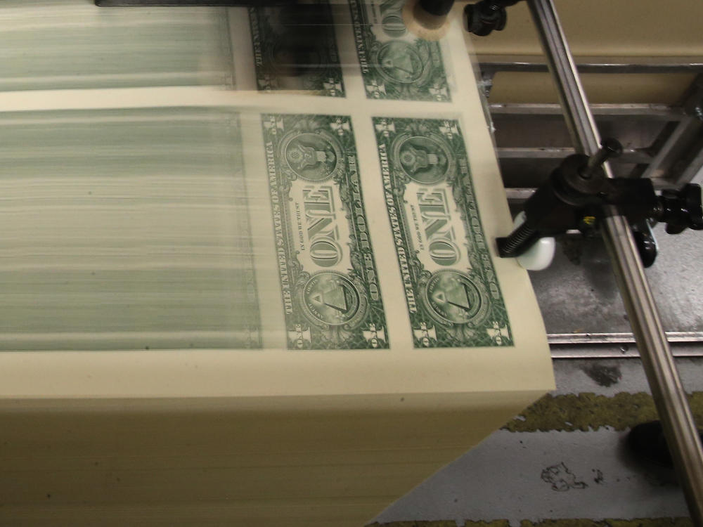 Sheets of one-dollar bills run through the printing press at the Bureau of Engraving and Printing in 2015 in Washington, D.C. Congressional forecasters projected the federal deficit this fiscal year will hit its highest since World War II.