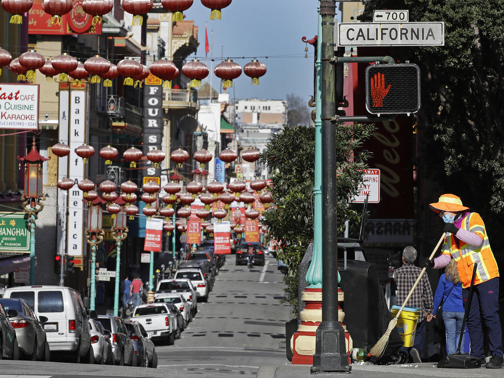 In this Jan. 31, 2020, file photo, a masked worker cleans a street in the Chinatown district in San Francisco. Police and volunteers have increased their street presence after a series of violent attacks against older Asian residents in Bay Area cities stoked fear and subdued the celebratory mood leading up to the Lunar New Year. (AP Photo/Ben Margot, File)