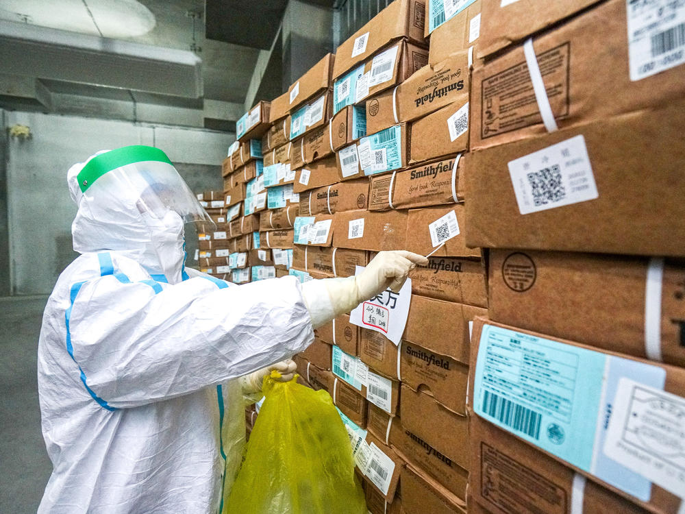 A health officer in a protective suit collects a sample from a package of imported frozen food for a coronavirus rapid test at a wholesale market in China.