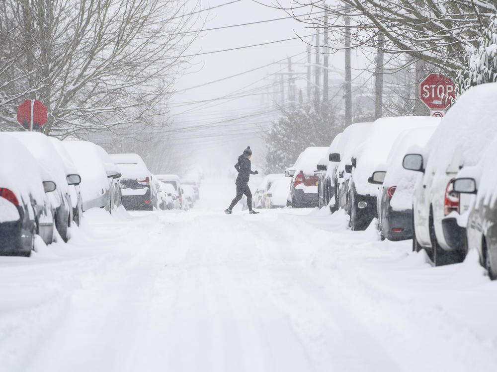 A jogger makes their way across a snowy street on Saturday in Seattle. A large winter storm dropped heavy snow across the region.