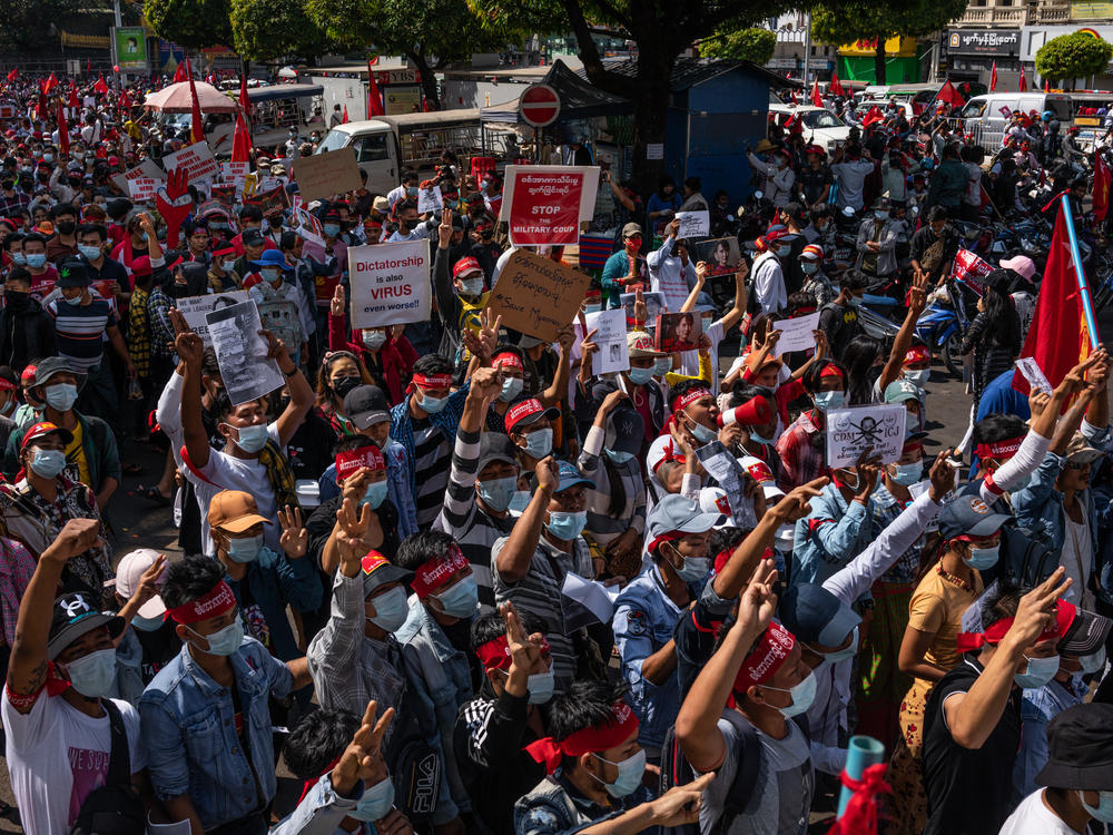 Protesters hold placards and shout slogans on Saturday in Yangon, Myanmar. Myanmar declared martial law in parts of the country, including its two largest cities, as protests continued to draw people to the streets after the military staged a coup.