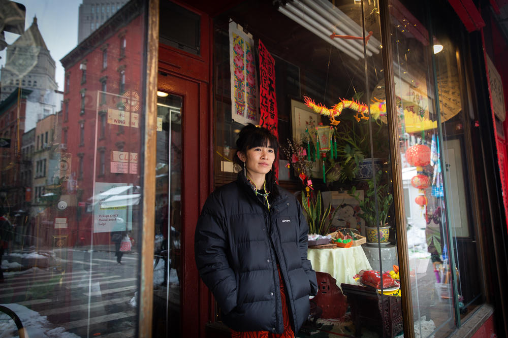 Mei Lum, the fifth generation owner of Wing on Wo porcelain shop, watches the festivities outside the store in Chinatown.