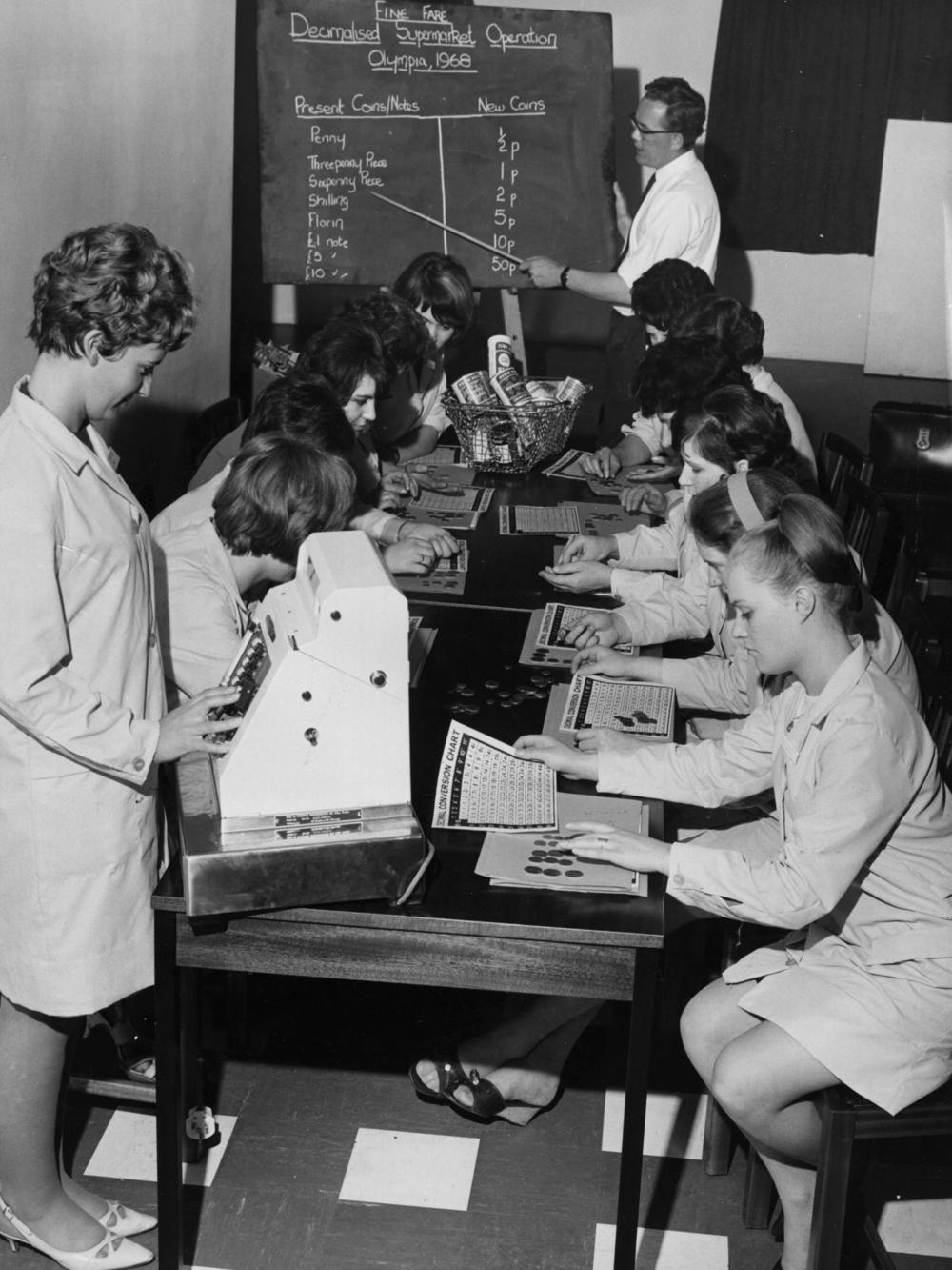 Checkout workers at a Fine Fare supermarket studying decimal conversion charts during a training course in 1968.