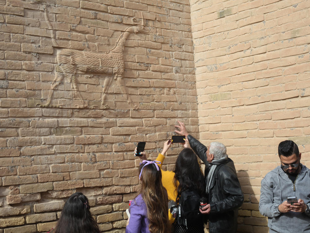 Visitors with the Bil Weekend tourism company take photographs inside the ruins of the ancient city of Babylon, in the area around the Ishtar gate. The animal on the walls ins a dragon-like creature associated with the Babylonian god Marduk.