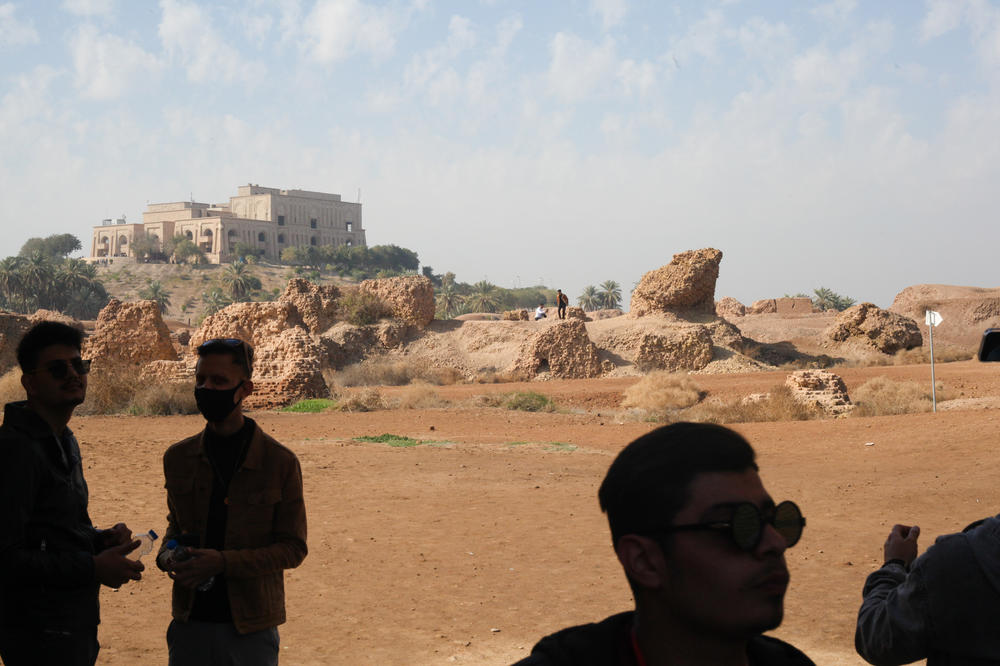 Visitors with the Bil Weekend tourism company take photographs at the site of the ancient ruins of Babylon, with a palace more recently built by Saddam Hussein in the background.