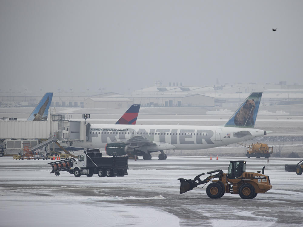Snow removal vehicles clear ice from around airplanes at Nashville International Airport on Monday, in Nashville, Tenn.