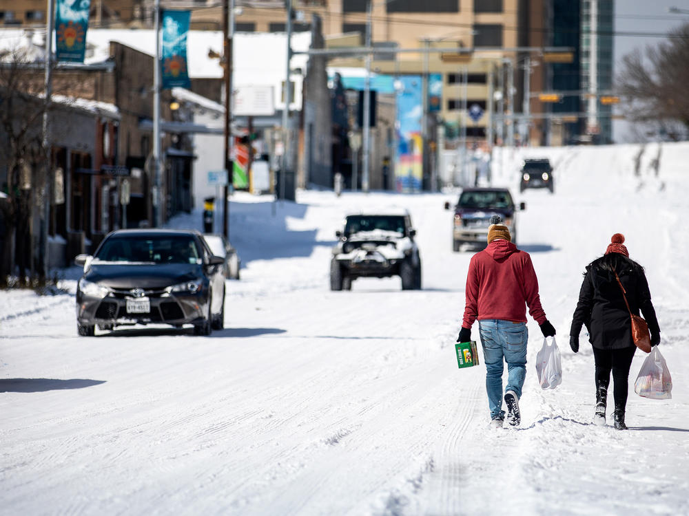 People carry groceries from a gas station on Monday in Austin, Texas. A winter storm has brought historic cold weather to the state, causing traffic delays and millions of customers to lose power.