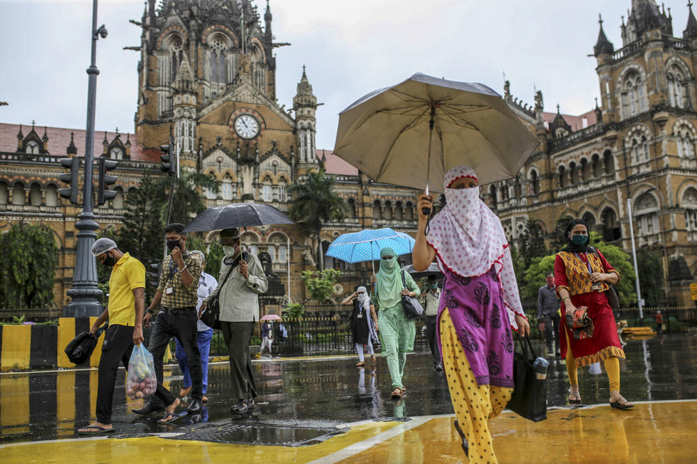Pedestrians wearing protective masks cross a road outside Chhatrapati Shivaji Maharaj Terminus railway station during the morning rush hour in Mumbai on July 14, 2020. Formerly Victoria Terminus, the railway station was built by the British to showcase Bombay's might.