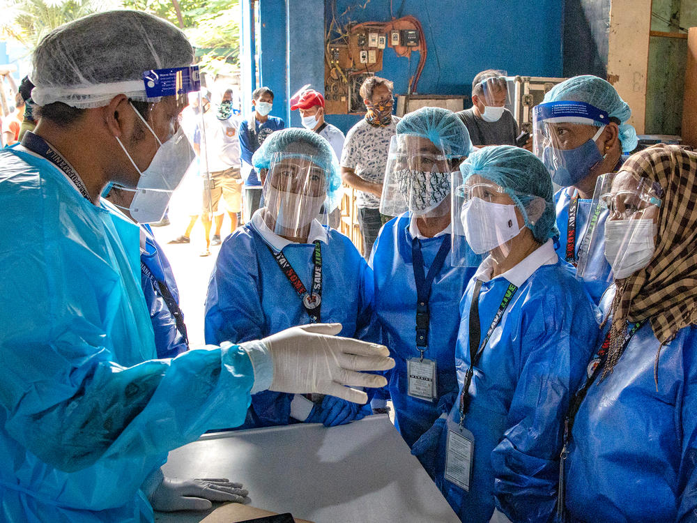 Health workers are briefed before conducting COVID-19 swab tests on public transportation drivers at a slum area in Manila. The Philippines is one of the Southeast Asian countries hit hardest by the pandemic.