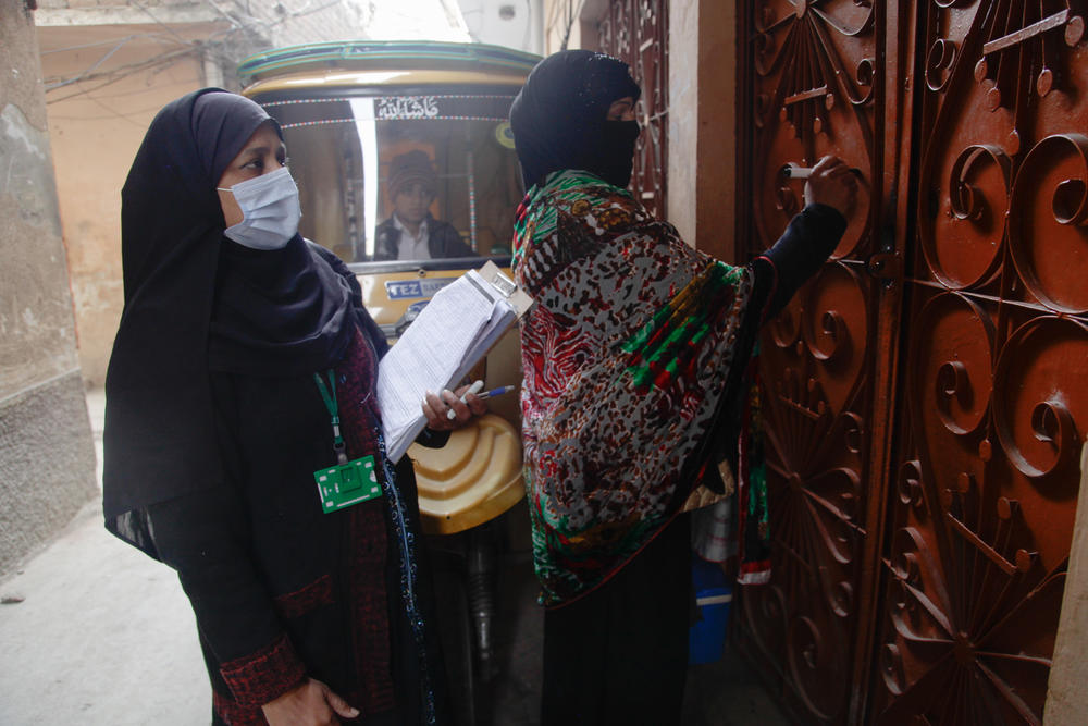 A volunteer working alongside Parveen records details of which children they vaccinated, and on which days, on the door of the family's home. Many doors in Pakistan have similar markings, which let health workers see at a glance how many children are in each house and when they were last vaccinated – or not.