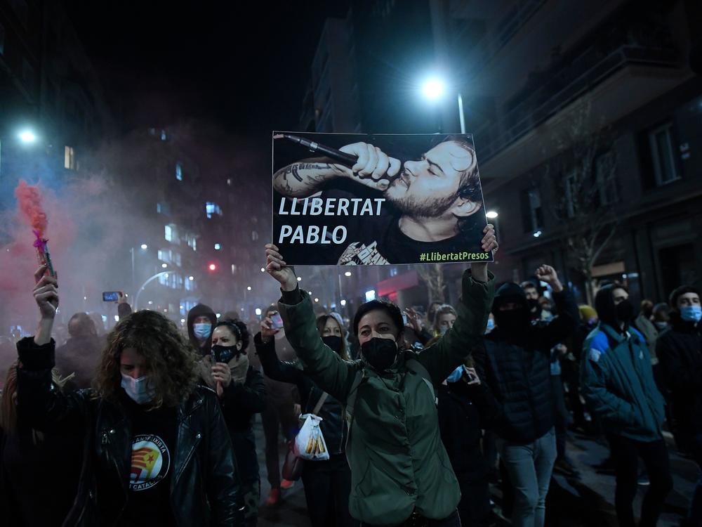 Protesters march with a picture of Spanish rapper Pablo Hasél reading 