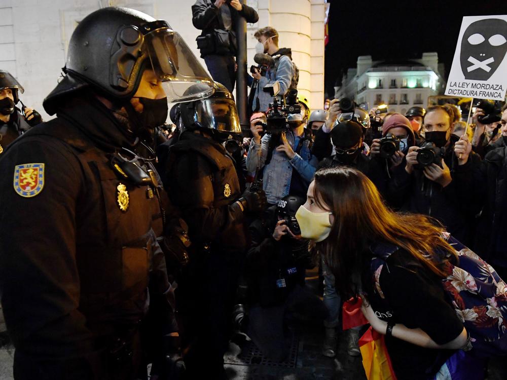 A woman talks to police during a demonstration against the imprisonment of Spanish rapper Pablo Hasél in Madrid. Clashes between police and protestors have gone on for three days and have led to dozens of arrests and injuries.