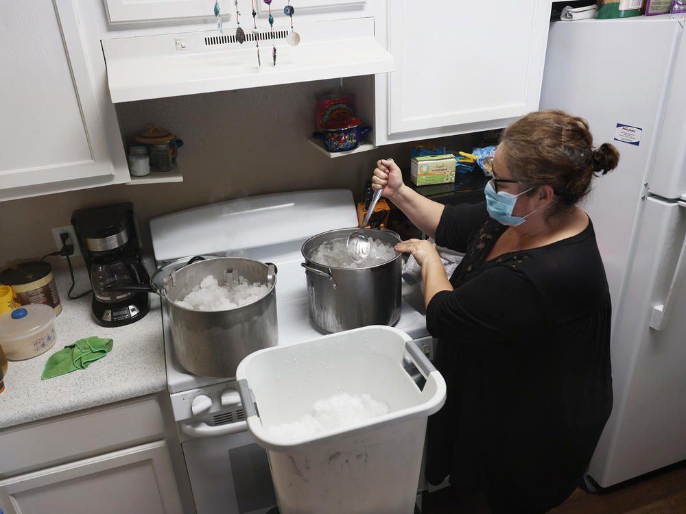 Marie Maybou melts snow on the kitchen stove on Friday in Austin, Texas. She was using the water to flush the toilets in her home after the city water stopped running.