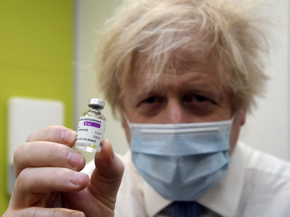Britain's Prime Minister Boris Johnson holds a vial of the AstraZeneca vaccine during a visit to a coronavirus vaccination center in London on Feb. 15, 2021. The British government hopes to vaccinate all adults by the end of July.