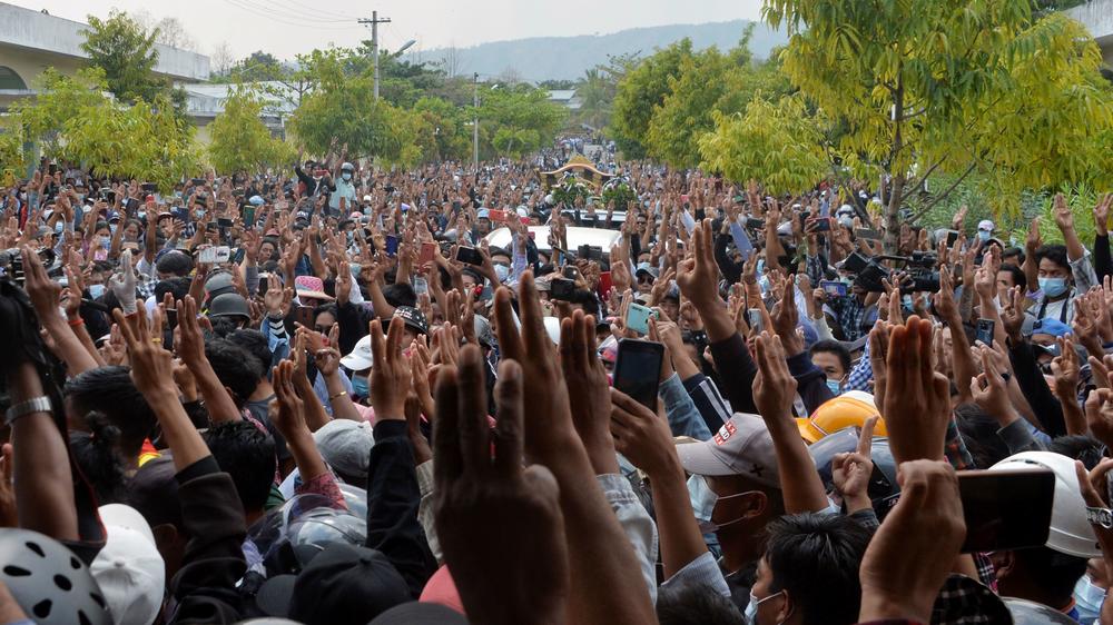 Mourners raise three fingers to the sky as the body of Mya Thwet Thwet Khine is taken to be buried. The gesture of solidarity, introduced in <em>The Hunger Games</em>, has been adopted by Myanmar activists.
