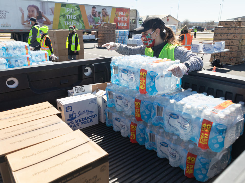 One week after winter storms triggered boil-water notices in Texas, more than 8.7 million people are still affected. Here, a volunteer loads food and bottled water at a mass distribution site in Del Valle, Texas.