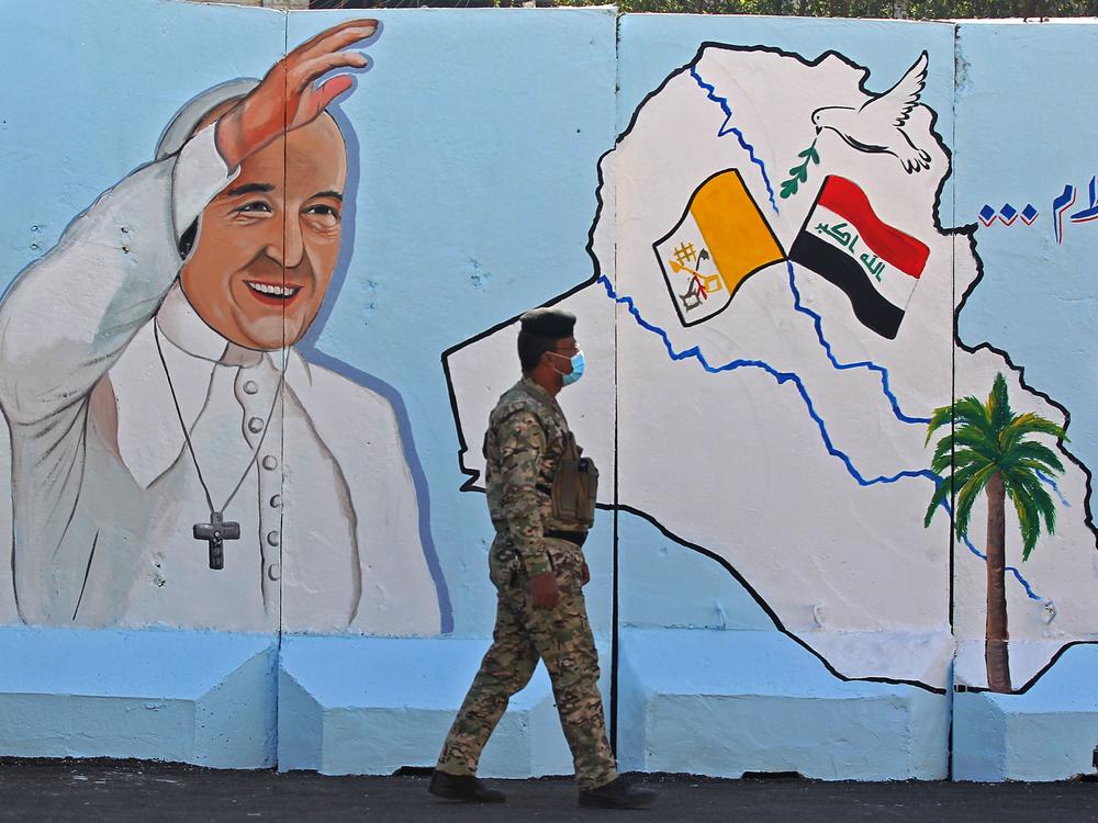An Iraqi policeman walks by a mural depicting Pope Francis on the outer walls of Our Lady of Salvation Church in Baghdad on Monday. Pope Francis' visit from March 5 to 8 will include trips to Baghdad, the city of Mosul and a meeting with the country's top Shiite cleric Grand Ayatollah Ali al-Sistani.