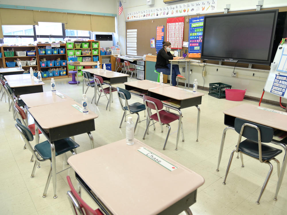 In this file photo, a New York City teacher wears a mask and teaches remotely from her classroom.